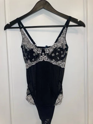 Vacker body i meshtyg och broderi  - Väldigt vacker body med svart meshtyg och vit broderi. Köpt på en marknad i Italien men är aldrig använd. Perfekt skick!  Är inte säker på om jag vill sälja än men skicka gärna prisförslag