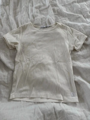 Ribbad vit t-shirt  - Säljer en enkel och stilren ribbad t-shirt i vit färg. T-shirten har korta ärmar, rund halsringning och är gjord i mjuk bomull. Perfekt basplagg till garderoben och lätt att matcha med allt.🤍🤍✨