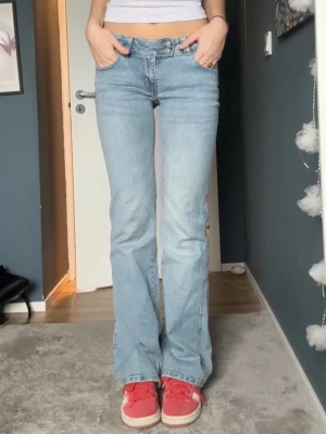 Ljusblå bootcut jeans med brodyr - Säljer ett par ljusblå bootcut jeans med snygg broderad detalj på bakfickan. Jeansen har klassisk femficksmodell, låg midja och är tillverkade i denim. Perfekta för en avslappnad och trendig look.