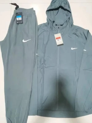 Nike grå träningsset med huva, kan mötas upp i malmö 📍 - Snyggt grått träningsset från Nike med matchande byxor och jacka med huva. Setet har dragkedja framtill och vita Nike-loggor på både jacka och byxa. Perfekt för träning eller sportiga dagar. Materialet är lätt och andas bra.