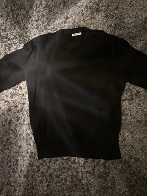 Svart stickad tröja från Zara - En stilren svart stickad tröja från Zara med rund halsringning och ribbade muddar vid ärmslut och nederkant. Perfekt basplagg för lager på lager och enkel att matcha med olika outfits. Bra skick
