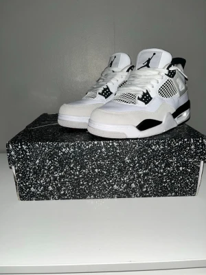 Air Jordan 4 Retro White/Black - Säljer ett par Air Jordan 4 Retro sneakers i vitt och svart med meshpaneler, läder och syntetmaterial. Klassisk Jumpman-logga på tungan och hälen, coola detaljer med plastvingar och synlig Air-dämpning i sulan. Perfekt för dig som vill ha en ikonisk och stilren look.kan prata pris vid snabb affär 