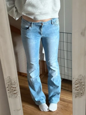 Ljusblå bootcut jeans från Only  - Säljer ett par ljusblå bootcut jeans med klassisk femficksdesign och normalhög midja. Jeansen har en snygg tvättad look och stängs med knapp och dragkedja. Perfekta för en avslappnad och trendig stil. Står storlek 32 passar mig som är 172