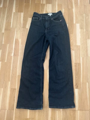 Mörkblå vida jeans från H&M - Snygga mörkblå jeans från H&M med hög midja och vida ben. Klassisk femficksmodell och raka sömmar. Perfekta för en avslappnad och trendig look. Tillverkade i ett mjukt denimtyg som ger en skön känsla hela dagen.