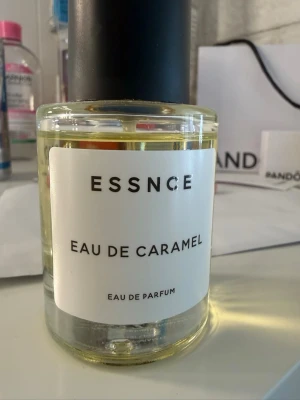 ESSNCE Eau de Caramel parfym - ESSNCE Eau de Caramel är en eau de parfum med söt karamell-doft. Flaskan är rund och genomskinlig med svart lock och vit etikett med stilren text. Perfekt för dig som gillar gourmanddofter och vill ha något unikt i parfymhyllan. Använd 2 gånger! Inte min typ av doft.