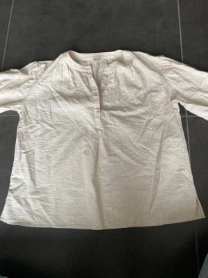 Vit strukturerad blus med knappar - PRIS KAN DISKUTERAS ❤️Säljer en vit blus med diskret rutstruktur och knappar framtill. Blusen har en avslappnad passform, rundad halsringning och långa ärmar. Perfekt att styla med jeans eller kjol för en clean look. 