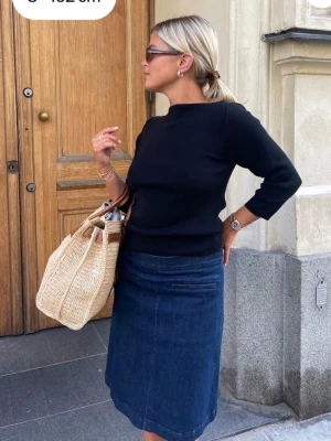 Mörkblå jeanskjol i klassisk modell - Säljer en mörkblå jeanskjol med rak passform och klassisk design. Kjolen har en enkel stil utan mönster och är tillverkad i denim, vilket gör den både snygg och enkel att matcha med olika toppar.