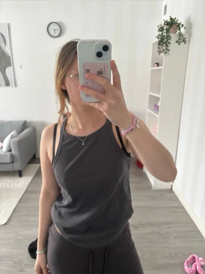 Mörkgrå linnetopp med breda axelband - Säljer en enkel och snygg mörkgrå linnetopp med breda axelband. Toppen är ärmlös och har en avslappnad passform som är perfekt för varma dagar. Materialet känns mjukt och bekvämt mot huden. Passar dig som gillar en clean och stilren look.