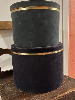 Två vintage hattaskar i sammet - Säljer två runda hattaskar i sammet, en mörkgrön och en mörkblå , båda med dekorativ guldfärgad kant. Perfekta för att förvara hattar eller accessoarer. Klassisk och stilren design som ger en lyxig känsla till rummet.