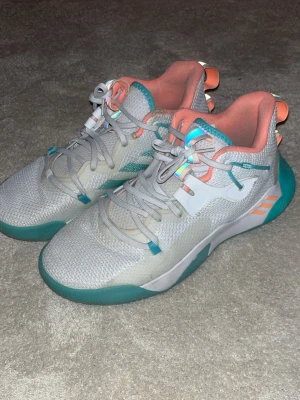 Basketskor - Snygga Adidas sneakers i vitt meshmaterial med turkosa och orange detaljer. Skorna har lågt skaft, vadderad insida i orange och robust sula i turkost. Perfekta för dig som gillar sportig och färgglad stil. James Hardens signature shoe Vol 6