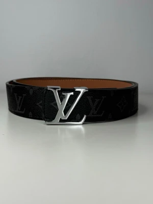 Exklusivt svart bälte med silver logga - Snyggt svart skärp i skinn med klassiskt monogram och silverfärgat logga. Insidan är ljusbrun och skärpet har en exklusiv känsla som lyfter vilken outfit som helst.