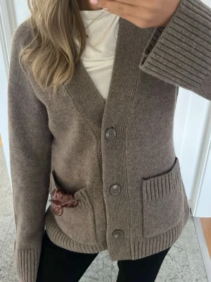 Beige kofta från Wera med fickor - Säljer min jätte fina stickade kofta från Wera med v-ringning, stora ribbade muddar och två framfickor. Nypris 899 kronor. Pris kan diskuteras!💖lånad bild