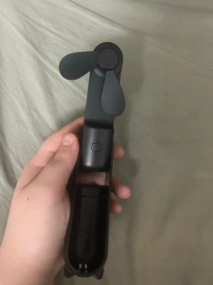 Svart hand fläkt supper bra motor bra för sommaren   - Säljer en svart portabel minifläkt med två blad. Fläkten är kompakt och hopfällbar, perfekt att ta med i väskan. Drivs via USB och har en enkel knapp på framsidan. Tillverkad i plast och har en stilren, modern design.