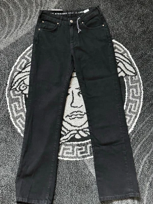 Svarta straight jeans från Weekday - Snygga svarta jeans från Weekday med rak passform och klassisk femficksdesign. Jeansen har hög midja och raka ben, perfekta till en avslappnad stil. Materialet är mjukt och stretchigt för extra komfort.