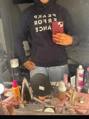 Mörkblå hoodie från Peak Performance - Säljer en mörkblå hoodie från Peak Performance med vit text på bröstet. Klassisk känguruficka framtill och huva. Super skön och fin utan defekter men ändå använd endel! Säljer då den inte kommer till användning🥰storlek 170 men ungefär som xs