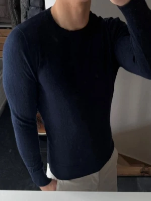 Mörkblå stickad tröja från a Days march - Mörkblå stickad tröja från a Days march med rund halsringning och långa ärmar. Tröjan har en smal passform och är tillverkad i mjukt material som passar perfekt till både jeans och chinos. Storlek m men har krympt så sitter som xs. Lite nopprig 