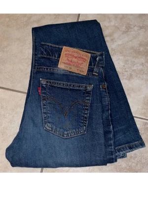 Levi's 529 blå jeans bootcut - Säljer ett par klassiska blå Levi's 529 jeans med bootcut passform. Jeansen har fem fickor, tydliga sömmar och den ikoniska röda Levi's-lappen på bakfickan. Tillverkade i slitstark denim med läderpatch bak i midjan. Perfekta för en avslappnad och tidlös stil. 