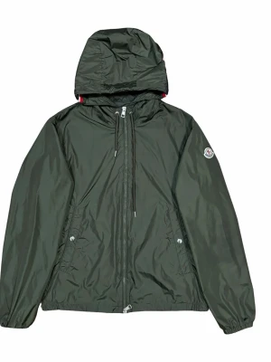 Svart vindjacka från Moncler - Stilren svart vindjacka från Moncler med huva och dragkedja framtill. Jackan har två sidofickor med knappstängning och ett broderat Moncler-märke på ärmen. Tillverkad i lätt, glansigt material som skyddar mot vind och regn. Perfekt för en sportig och trendig look.