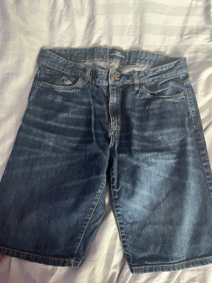 Blå jeansshorts från Hampton Republic - Snygga blå jeansshorts från Hampton Republic med klassisk femficksdesign och knappgylf. Shortsen har en rak passform och är tillverkade i slitstark bomull. Perfekta för en avslappnad stil under varmare dagar. Se måttet på bilderna. 