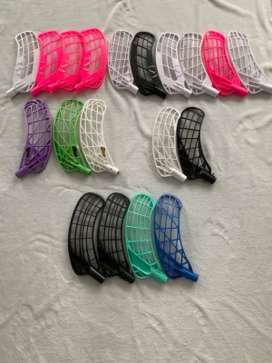 Innebandyblad i mixade färger - Säljer ett gäng innebandyblad i olika färger som rosa, vit, svart, grön, lila, blå och turkos. Bladen är tillverkade i plast och har klassisk form med rutmönster för bra bollkontroll. Perfekt för dig som vill byta stil eller behöver reservblad till innebandyklubban.