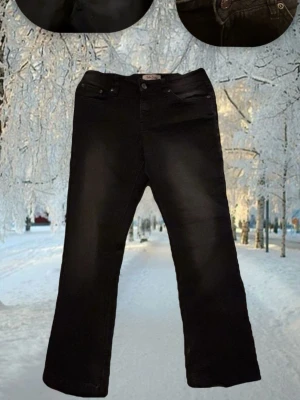 Svarta bootcut jeans - Säljer ett par svarta bootcut jeans med klassisk femficksdesign och knappgylf. Jeansen har en lätt utsvängd passform nedtill och är perfekta för en avslappnad men ändå trendig look. Materialet är denim med en mjuk känsla.