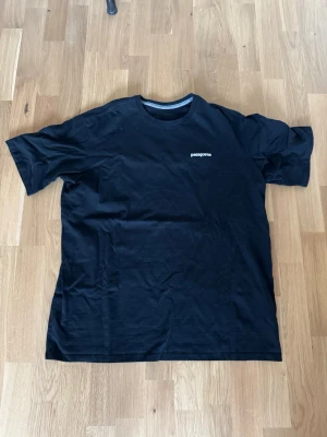 Svart och vit och blå Patagonia t-shirt - 3 st klassiska t-shirts från Patagonia i svart och vit och en blå. Båda har rund hals, korta ärmar och en liten logga på bröstet. Perfekta basplagg i mjuk bomull som funkar till allt. Enkel och stilren design som alltid är rätt.