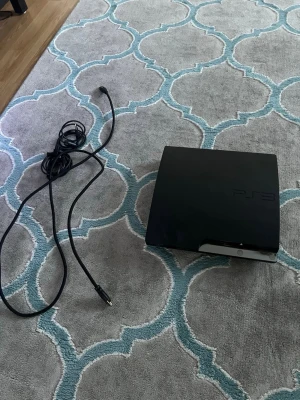 PlayStation 3 Slim svart konsol - Säljer en svart PlayStation 3 Slim från Sony. Konsolen har en stilren, matt finish och rundade kanter. Medföljer gör en strömkabel. Perfekt för dig som vill spela klassiska PS3-spel eller streama media. Och tyvärr konsoller funkar inte