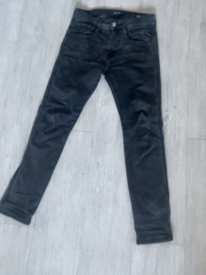 Svarta jeans från replay - Säljer ett par svarta jeans från replay med klassisk femficksmodell och smal passform. Jeansen har normal midja och är tillverkade i stretchigt material för extra komfort. Perfekta för en clean och stilren look.