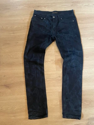 Svarta jeans från Nudie Jeans - Säljer ett par unika svarta jeans från Nudie Jeans med klassisk femficksmodell och raka ben. Jeansen har en diskret logga på bakfickan och är gjorda i denim. Perfekta för dig som gillar en stilren och enkel look.                                                             Bara att höra av sig vid frågor om tex mått.                   Pris kan diskuteras vid snabb affär 