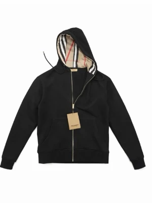 Svart hoodie från Burberry med dragkedja - Snygg svart hoodie från Burberry med dragkedja och klassiskt randigt foder i huvan. Hoodien har känguruficka framtill, ribbade muddar och en stilren look. Perfekt för dig som gillar exklusiva streetwear-plagg med ikoniska detaljer. Storlek s