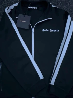  Palm Angel - Svart hoodie från Palm Angels med vit dragkedja och vita ränder. PRISET EJ HUGGET I STEN