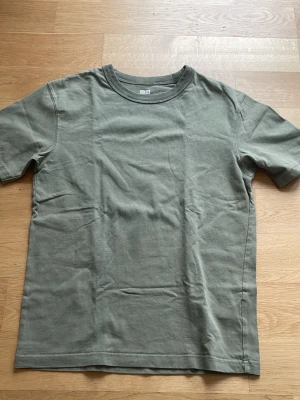 Grågrön basic t-shirt - Enkel t-shirt i grågrön färg med korta ärmar och rund hals. Modellen är rak och avslappnad, perfekt för en clean och stilren look. Tillverkad i mjukt bomullstyg som känns skönt mot huden.