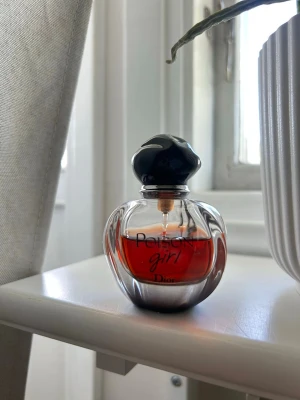 Poison Girl parfym från Dior - Säljer en Poison Girl parfym från Dior. Flaskan är rund och genomskinlig med en mörk kork och rödbrun vätska inuti. Märkets logga och namn syns tydligt på framsidan. Perfekt för dig som gillar lyxiga dofter.