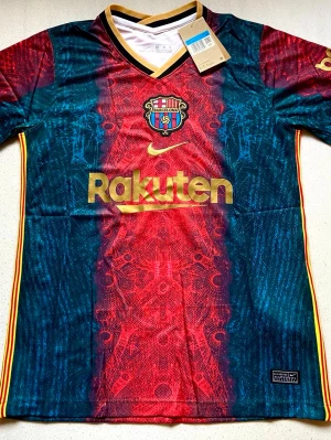 FC Barcelona matchtröja Nike - Säljer en FC Barcelona matchtröja från Nike med unikt rödblått mönster, guldfärgade detaljer och klubbmärke på bröstet. Rakuten och Unicef-loggor i guld, samt guldfärgad V-ringning och ärmkanter. Perfekt för dig som älskar fotboll och vill sticka ut på planen.