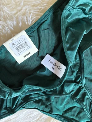 Gröna trosor från Bikbok, her[body] - Snygga gröna trosor från Bikbok, kollektionen her[body], i storlek XS. Modellen är högmidjad med klassisk passform och tillverkad i ett mjukt och stretchigt material som sitter bekvämt hela dagen.