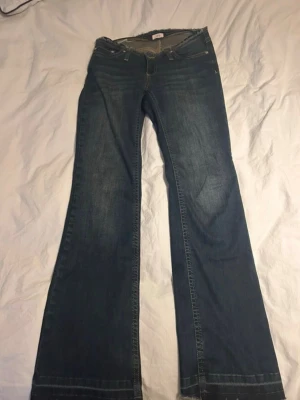No waist jeans  - Säljer ett par blå bootcut jeans med låg midja och klassisk femficksdesign. Jeansen har en lätt tvättad look och vida ben som ger en retro känsla. Perfekta för dig som gillar en avslappnad och trendig stil.