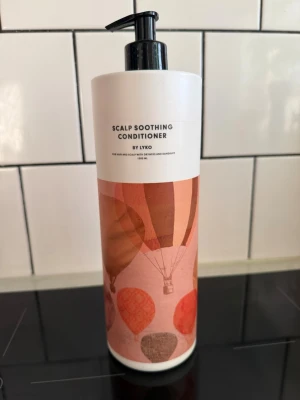 Lyko Scalp Soothing Conditioner - Stor flaska Scalp Soothing Conditioner från Lyko med pump. Balsamet är speciellt framtaget för att lugna hårbotten och motverka mjäll. Flaskan är vit med färgglad ballongdesign i orange och rosa toner. Innehåller 1000 ml.