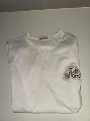 Vit Moncler t-shirt med logga - Moncler double logo T-shirt i storlek small. Jättebra skick, knappt använd, inga defekter eller likande. Äkthet går att kontrollera med qr koden som finns på etiketten (se bild).