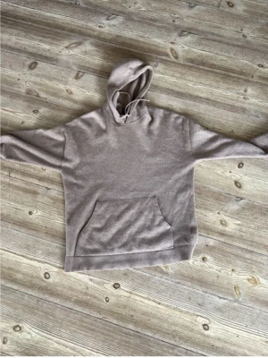 Beige hoodie i kashmir från Massimo Dutti - Mysig beige hoodie från Massimo Dutti i 100% kashmir. Klassisk modell med huva, dragsko och stor magficka framtill. Perfekt för en chill och stilren look. 