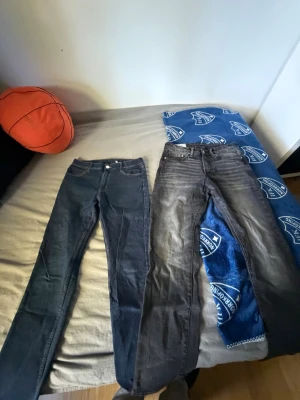 Två par jeans i blått och grått -  Säljer två par jeans, som är runt 176 så passar dig som är runt 170 till 185.  Kontakta om ni bara vill ha ett par De är ett i klassiskt mörkblå denim och ett i tvättad grå färg. Båda har smal passform och femficksdesign. Perfekta för dig som gillar en enkel och stilren look till vardags. Materialet är denim med stretch för extra komfort.