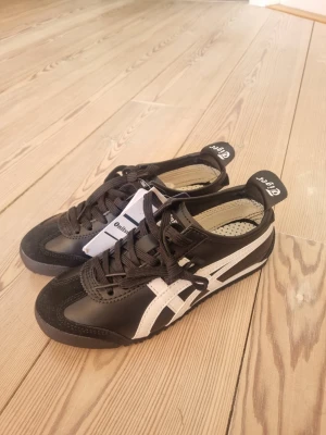Onitsuka Tiger svart - Klassiska Onitsuka Tiger, svarta vita stripes på sidorna. Aldrig använda, säljer pga för små!