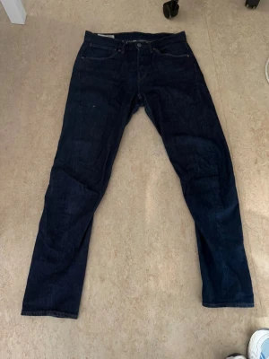 Mörkblå Levi's jeans herr - Säljer ett par klassiska mörkblå jeans från Levi's med rak passform. Jeansen har fem fickor, knappgylf och tydliga sömmar på bakfickorna. Perfekta för dig som gillar en tidlös och stilren look.