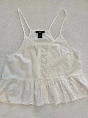 H&M vit broderad topp / peplum linne strl 34 - Söt vit topp från H&M i storlek 34 🤍 Lätt och somrig modell med tunna axelband, broderade detaljer och peplum/volang nedtill. 
