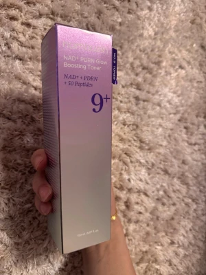 NAD+ PDRN Glow Boosting Toner 9+ - Glow Boosting Toner från Philosophy med NAD+, PDRN och 50 peptider. Kommer i en snygg, skimrande lila och silverfärgad förpackning på 150 ml. Perfekt för dig som vill ha extra lyster och vård i din hudvårdsrutin.