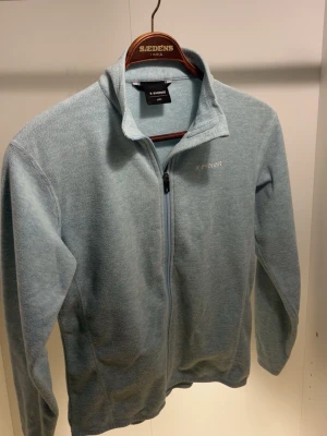 Ljusblå fleecejacka Everest - Mysig ljusblå fleecejacka från Everest med hel dragkedja framtill och hög krage. Tillverkad i mjukt fleecematerial som håller värmen. Perfekt för lager-på-lager och enkel att matcha med andra plagg.