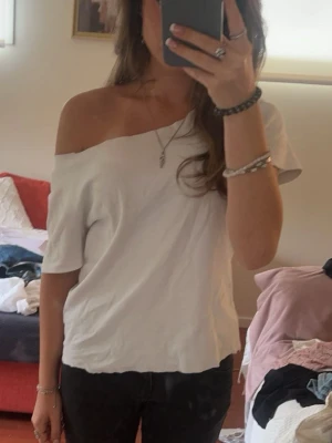 Vit offshoulder topp - Snygg vit offshoulder topp med kort ärm och avslappnad passform. Perfekt för en trendig och avslappnad look. Enkel att matcha med både jeans och kjol.