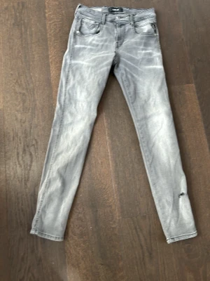 Grå skinny jeans från Replay - Snygga grå skinny jeans från Replay med slitningar och tvättad look. Jeansen har klassisk femficksdesign och smal passform som sitter tajt längs benen. Perfekta för en trendig och avslappnad stil.
