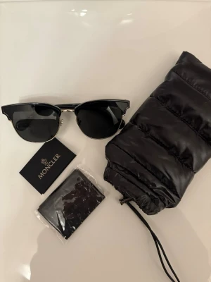 Moncler solglasögon - äkta, mycket fint skick (nypris 3.500)) - Äkta Moncler solglasögon. Mycket fint skick – inga repor, endast lätt damm som enkelt torkas bort.  Har legat i medföljande original fodralet sedan köp.   Medföljer: ✔ Originalfodral ✔ Rengöringsduk ✔ Äkthetskort  Nypris ca 3 500  kr. Säljes p.g.a. att de inte används och hittades vid flytt. Kan skicka fler bilder vid önskemål.  #moncler #monclerglasögon #solglasögon #designer #lyx #premiumÄkta Moncler solglasögon.