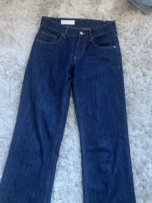 Mörkblå raka jeans från Zara - Snygga mörkblå jeans från zara med rak passform och klassisk femficksdesign. Jeansen har hög midja, silverfärgade nitar och kontrastsömmar. Tillverkade i kraftig denim som ger en tidlös look.