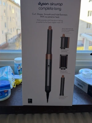 Dyson Airwrap Complete Long hårstyler - Dyson Airwrap Complete Long är ett multifunktionellt hårstylingverktyg i svart och koppar. Setet innehåller flera tillbehör: smoothing dryer, 30mm och 40mm lång cylinder, fast borste, mjuk borste och rund volymborste. Perfekt för att skapa lockar, volym och släta frisyrer utan extrem värme.